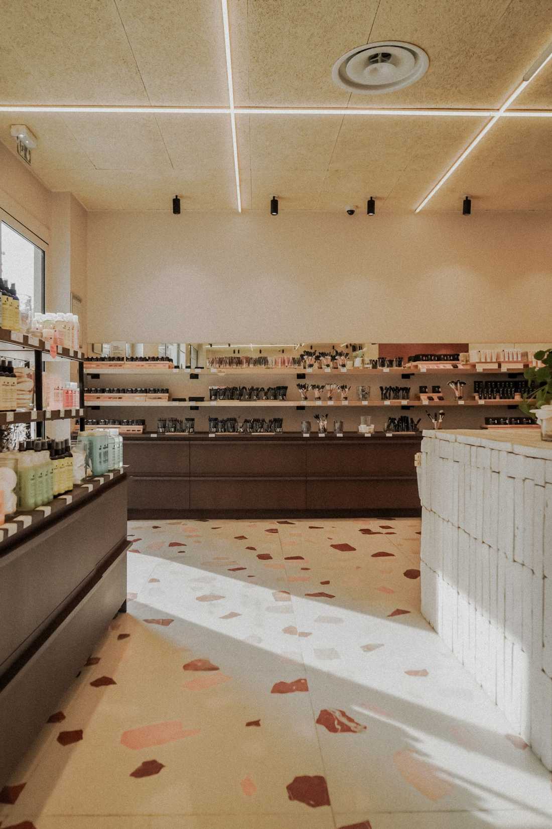 Sol en terrazzo et comptoir en briques blanchies dans la boutique de cosmétiques Avril