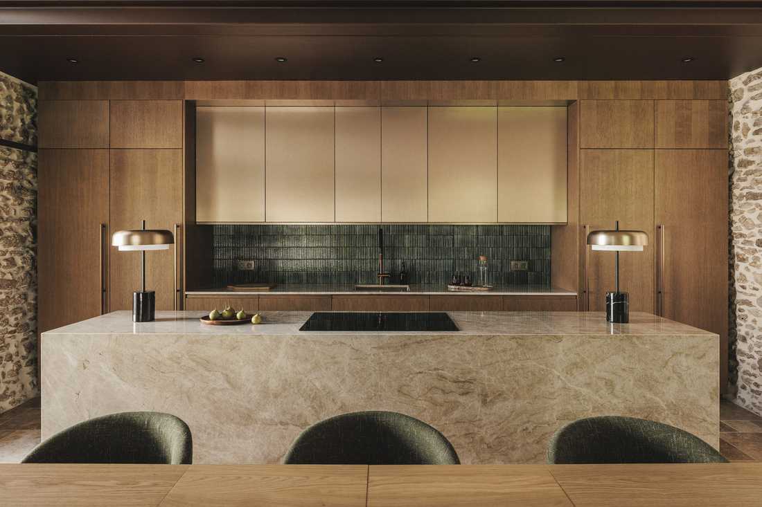 Rénovation complète d’une longère au cœur de la forêt - l'îlot de cuisine et les assises en velours vert