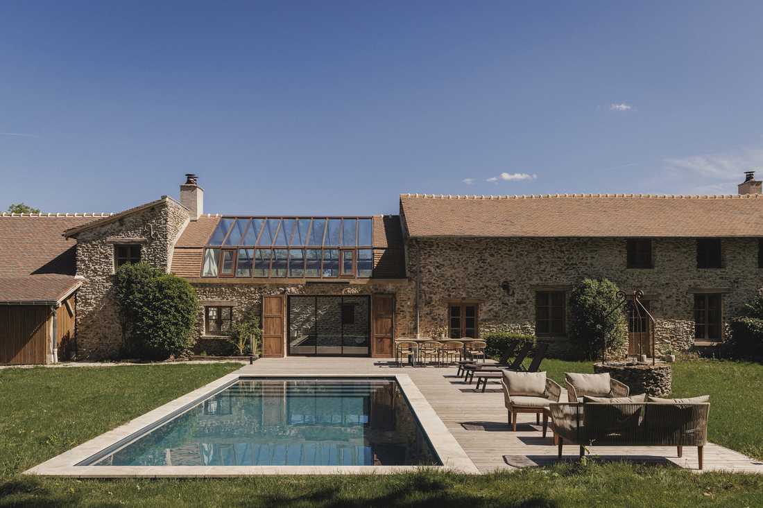 Création d’une piscine dans le jardin d’une longère - la piscine, le salon extérieur et la verrière de l'ancienne grange