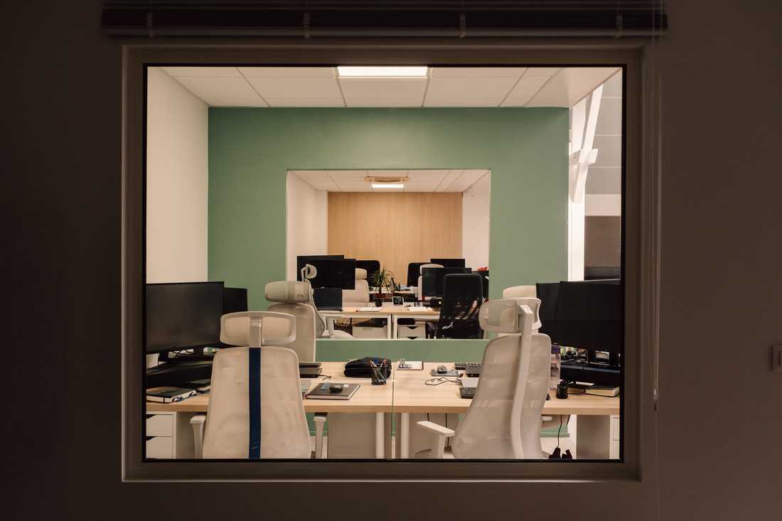 Aménagement du siège social d'une startup - Open space et mur vert vus depuis l'atrium
