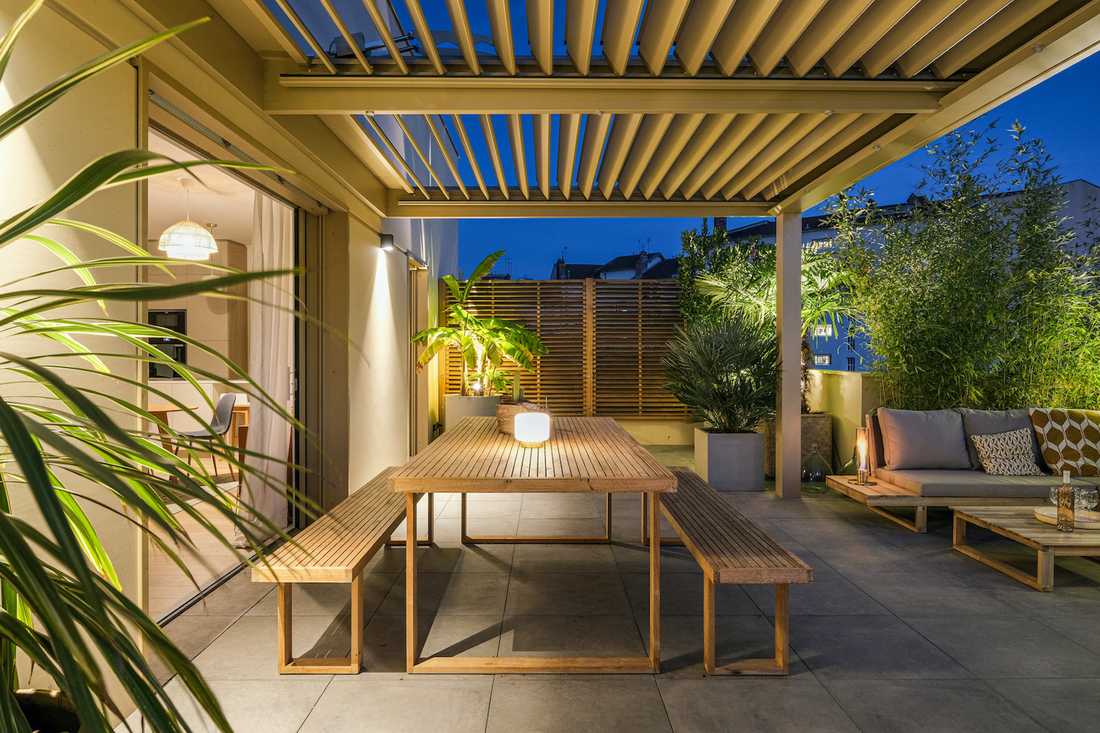 Terrasse bioclimatique avec pergola - espace repas avec vue vers l'intérieur - vue nocturne