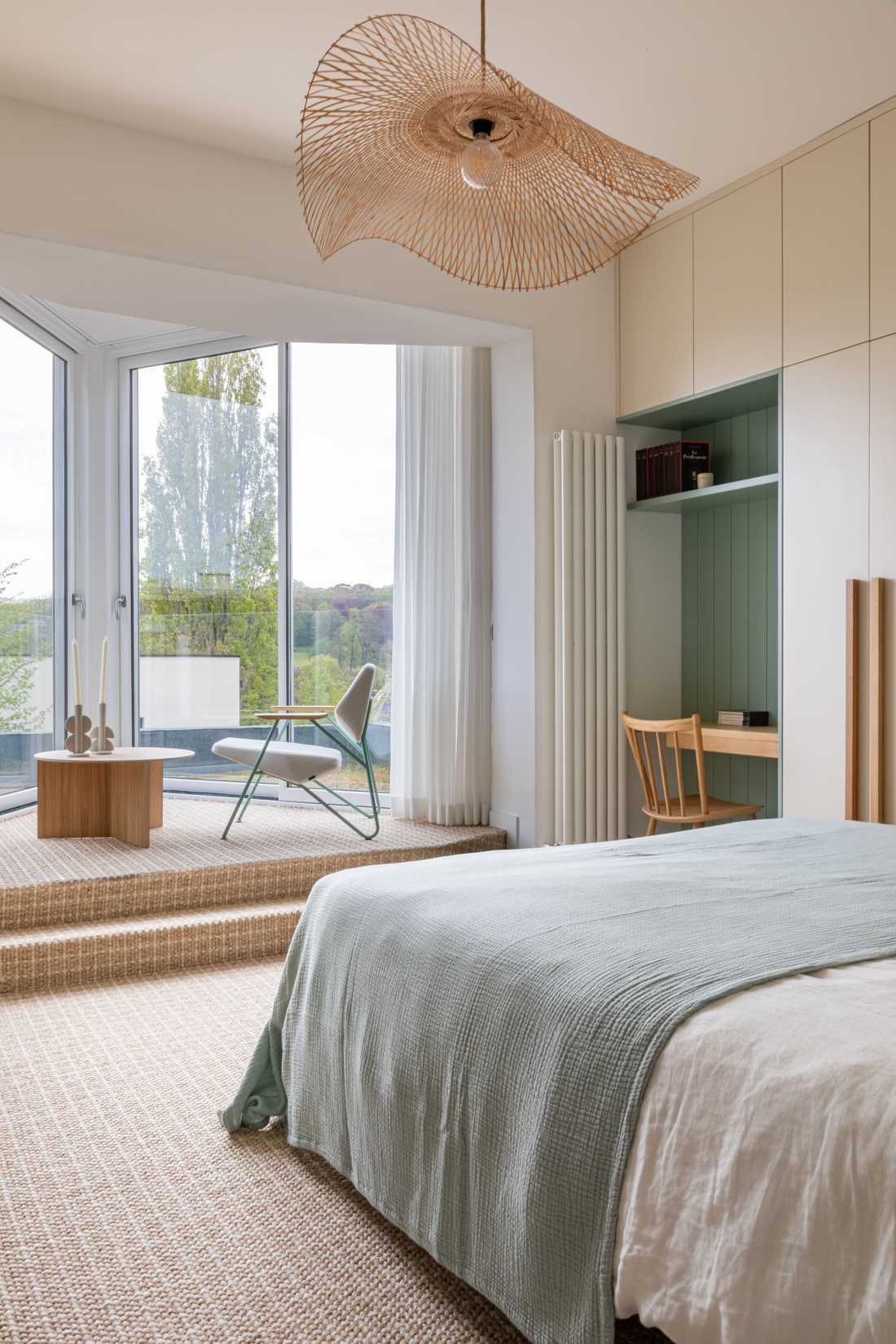 Chambre avec coin lecture devant une baie vitrée