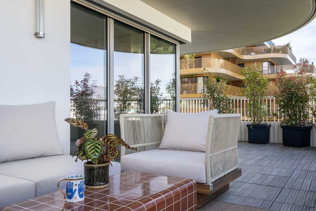 Salon d'extérieur sur la terrasse, avec fauteuil en corde tressée et table basse carrelée