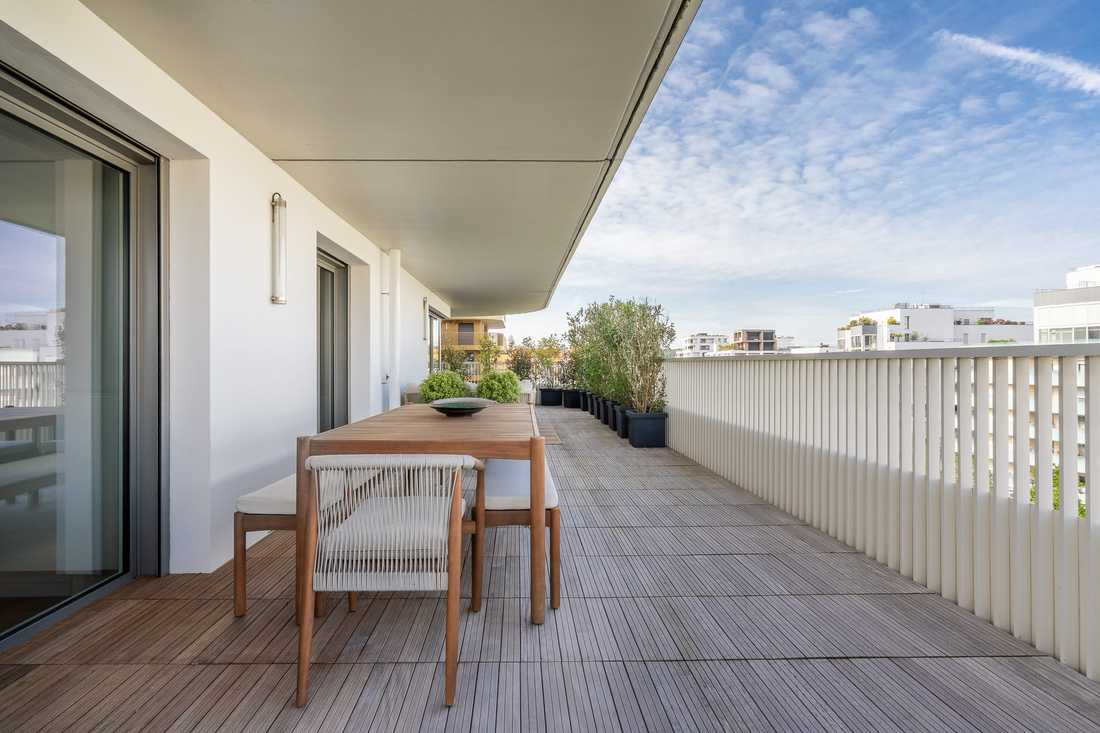 Grande terrasse en bois avec table à manger et jardinières le long du garde-corps