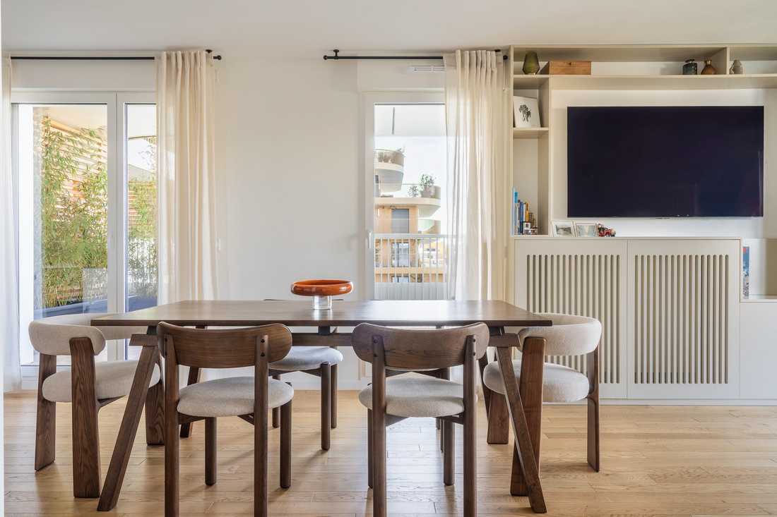Salle à manger avec table en bois foncé, à côté du meuble TV sur mesure