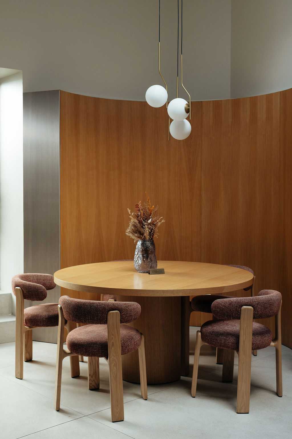 Table ronde en bois et chaises dans la salle du restaurant L'Art du Festin