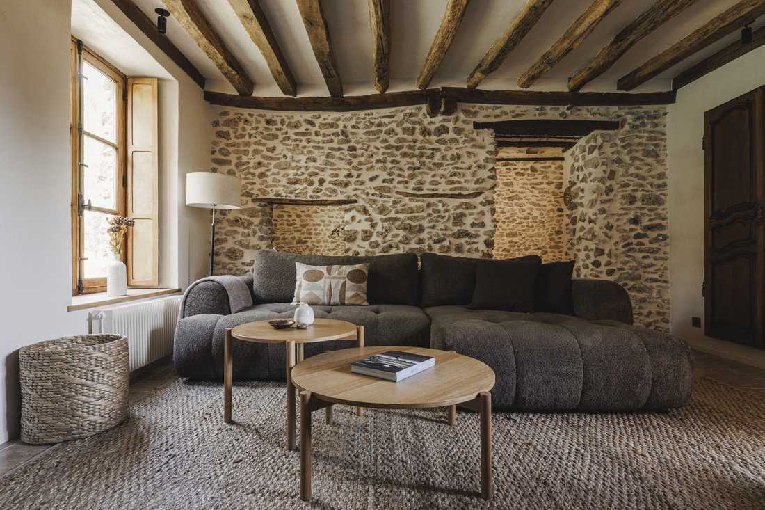 Rénovation complète d’une longère au cœur de la forêt - le second salon avec canapé en bouclette et poutres apparentes