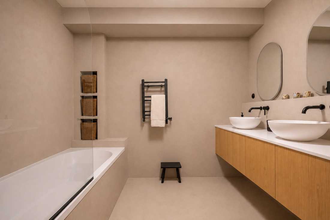 Salle de bain principale en béton ciré beige avec baignoire et double vasque