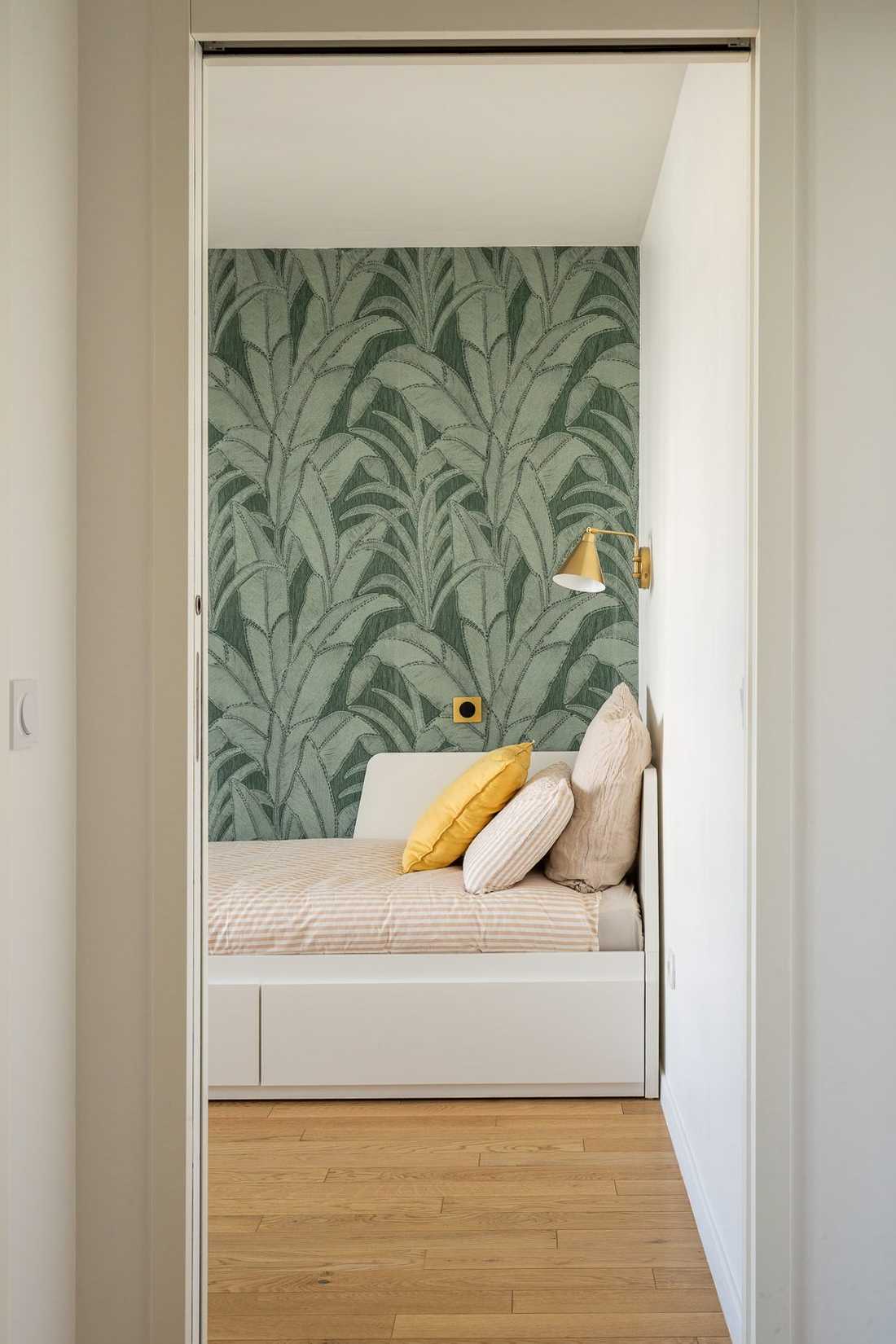 Chambre d'amis avec papier peint végétal vert, vue depuis la porte à galandage