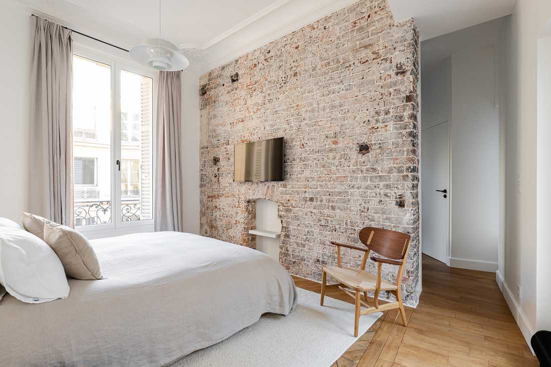 Chambre d'un appartement familial haussmannien avec mur en brique