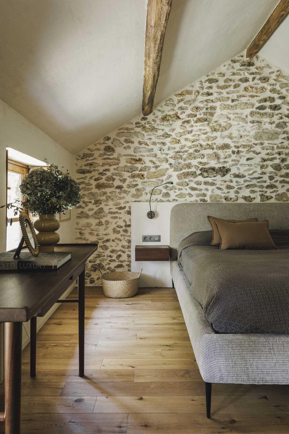Rénovation complète d’une longère au cœur de la forêt - une chambre sous les combles avec mur en pierre