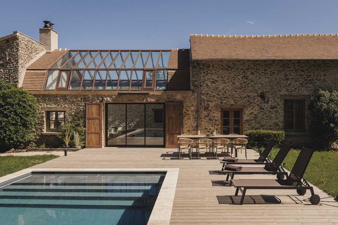 Création d’une piscine dans le jardin d’une longère - la terrasse en bois et les bains de soleil le long de la piscine