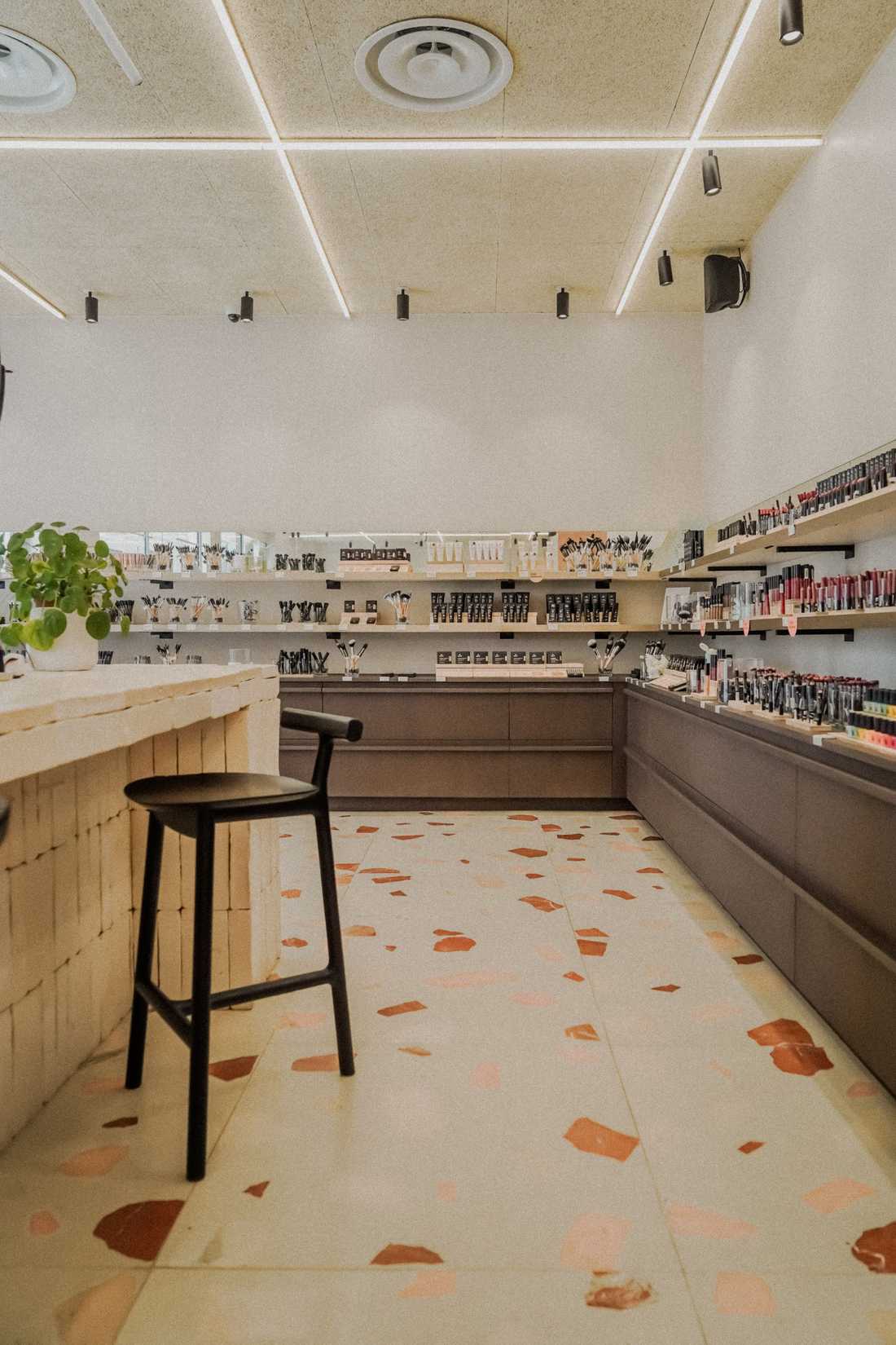 Enduit à la chaux et plafond en bois souligné de lignes lumineuses au-dessus des présentoirs de la boutique