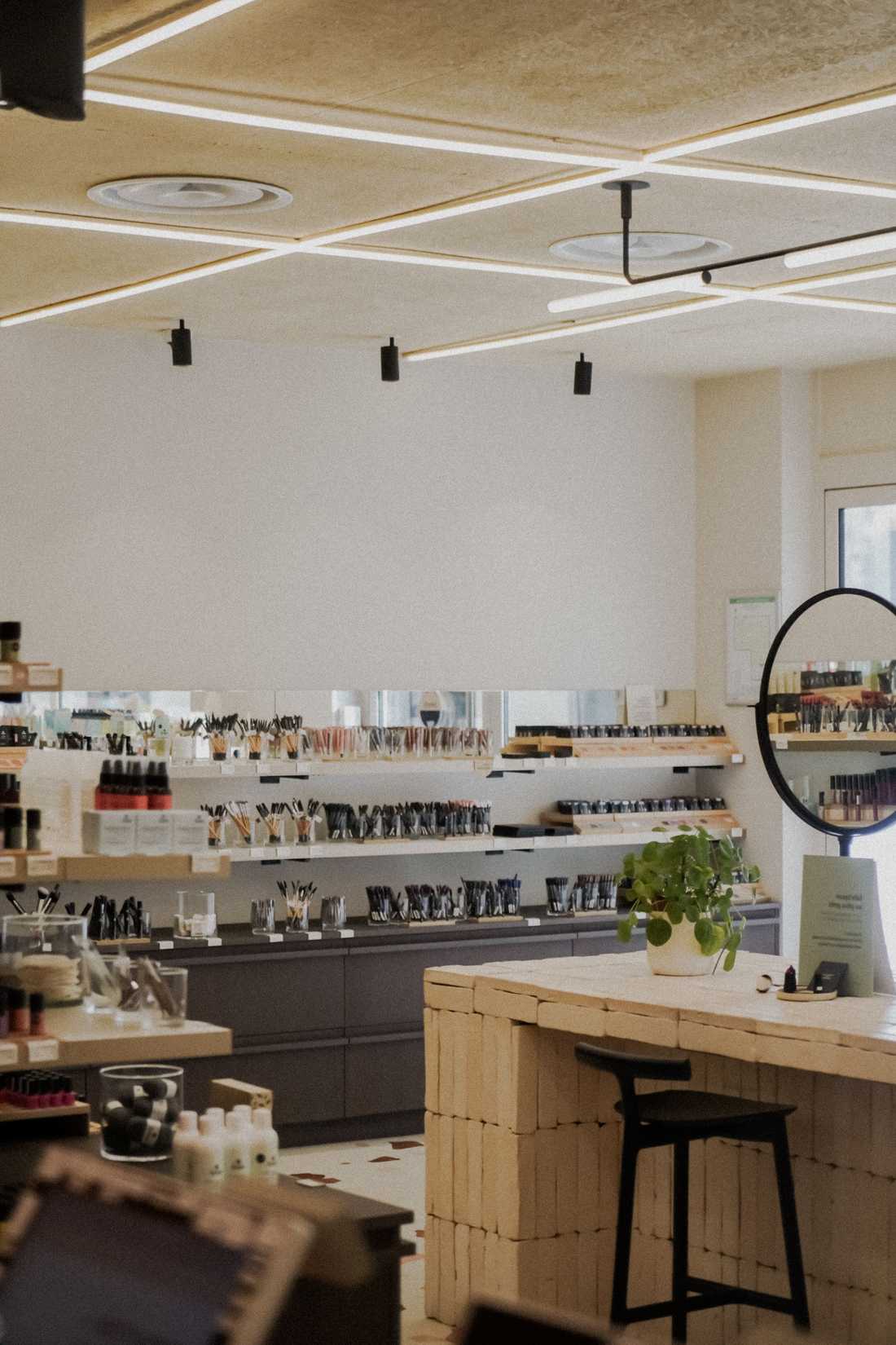 Îlot central de la boutique de cosmétiques avec comptoir en briques blanchies et miroir rond