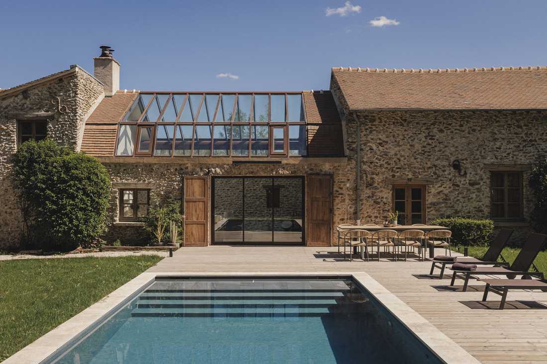 Création d’une piscine dans le jardin d’une longère - la piscine aux margelles en pierre claire face à la verrière