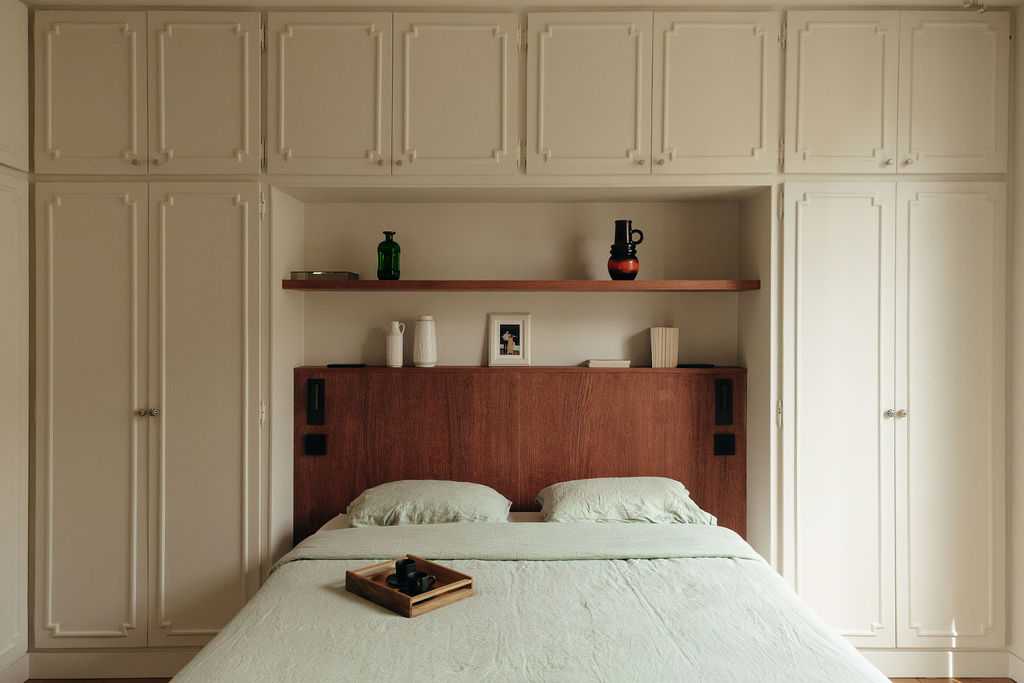 Restructuration d'un appartement à Paris 17 - la chambre avec tête de lit en bois et placards avec moulures